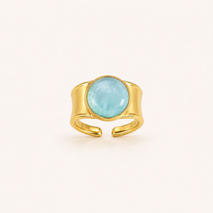 Anillo Bruma dorado ajustable con cabujón azul claro sobre fondo blanco