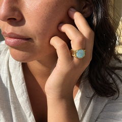 Anillo Bruma dorado ajustable con cabujón azul puesto en una mano