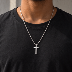 Collar Creed plateado de 60 cm con cruz lisa de unos 4 cm sobre camiseta negra