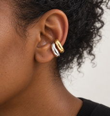 Earcuffs Ímpetu dorado y plateado en la oreja de una modelo negra.