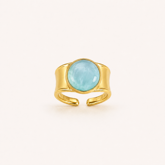 Anillo Bruma dorado ajustable con cabujón azul claro sobre fondo blanco