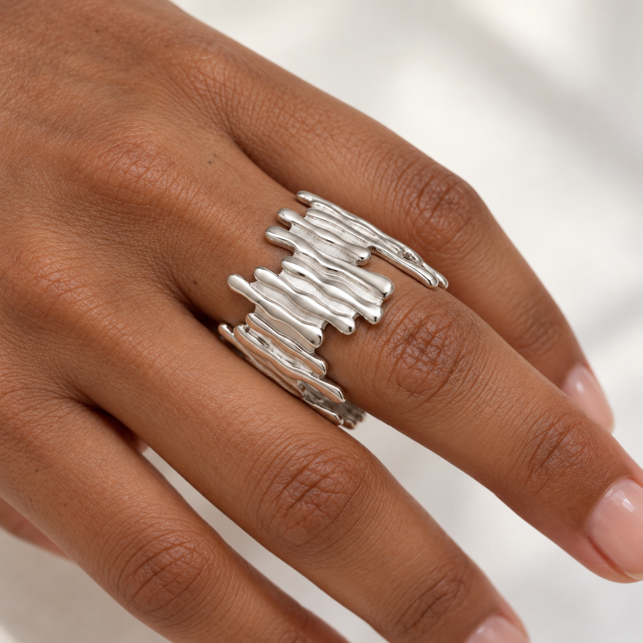 Anillo Distorsión plateado ajustable de relieve ondulado en una mano morena