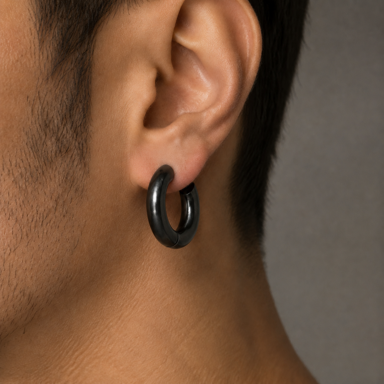 Aro Blackout grande pavonado negro centrado en el lóbulo de una oreja masculina