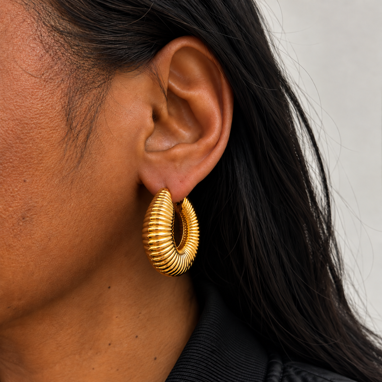 Aro Obriza chunky dorado con relieve acanalado, colocado en el lóbulo y proporcionado a la oreja