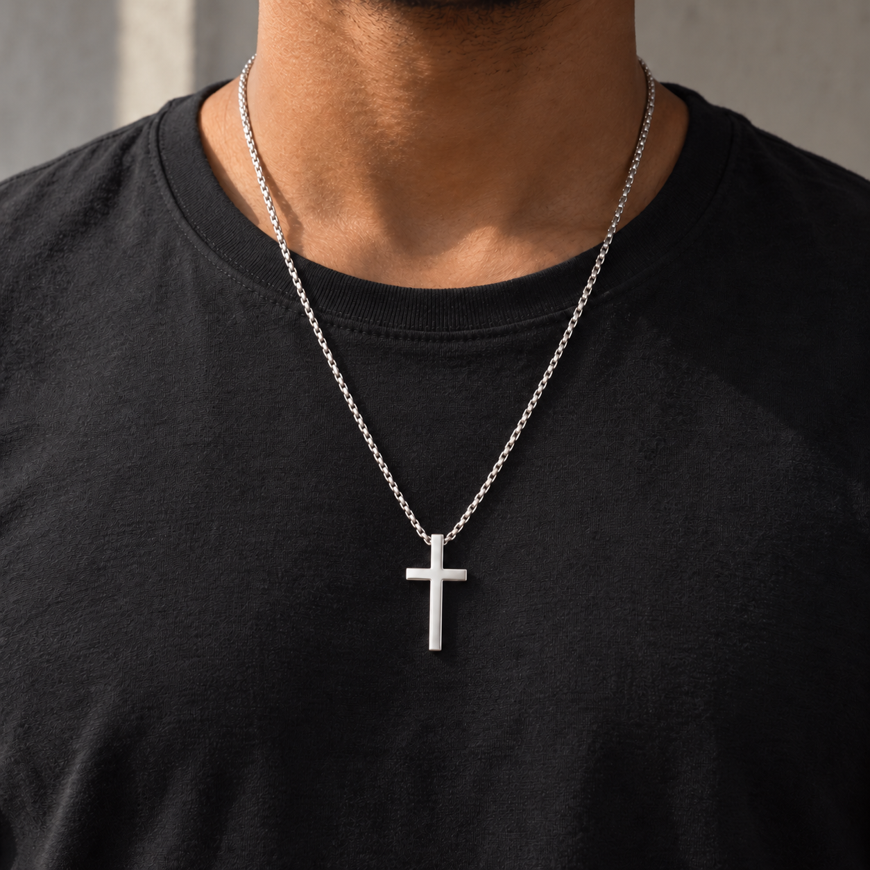 Collar Creed plateado de 60 cm con cruz lisa de unos 4 cm sobre camiseta negra