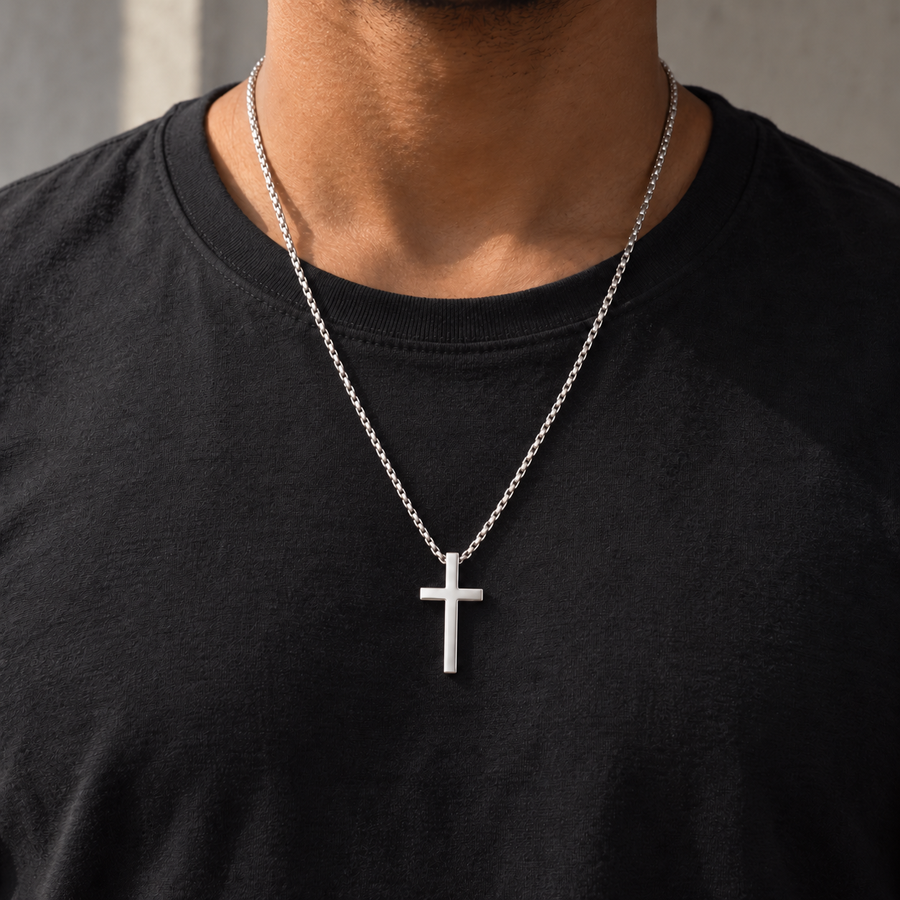Collar Creed plateado de 60 cm con cruz lisa de unos 4 cm sobre camiseta negra