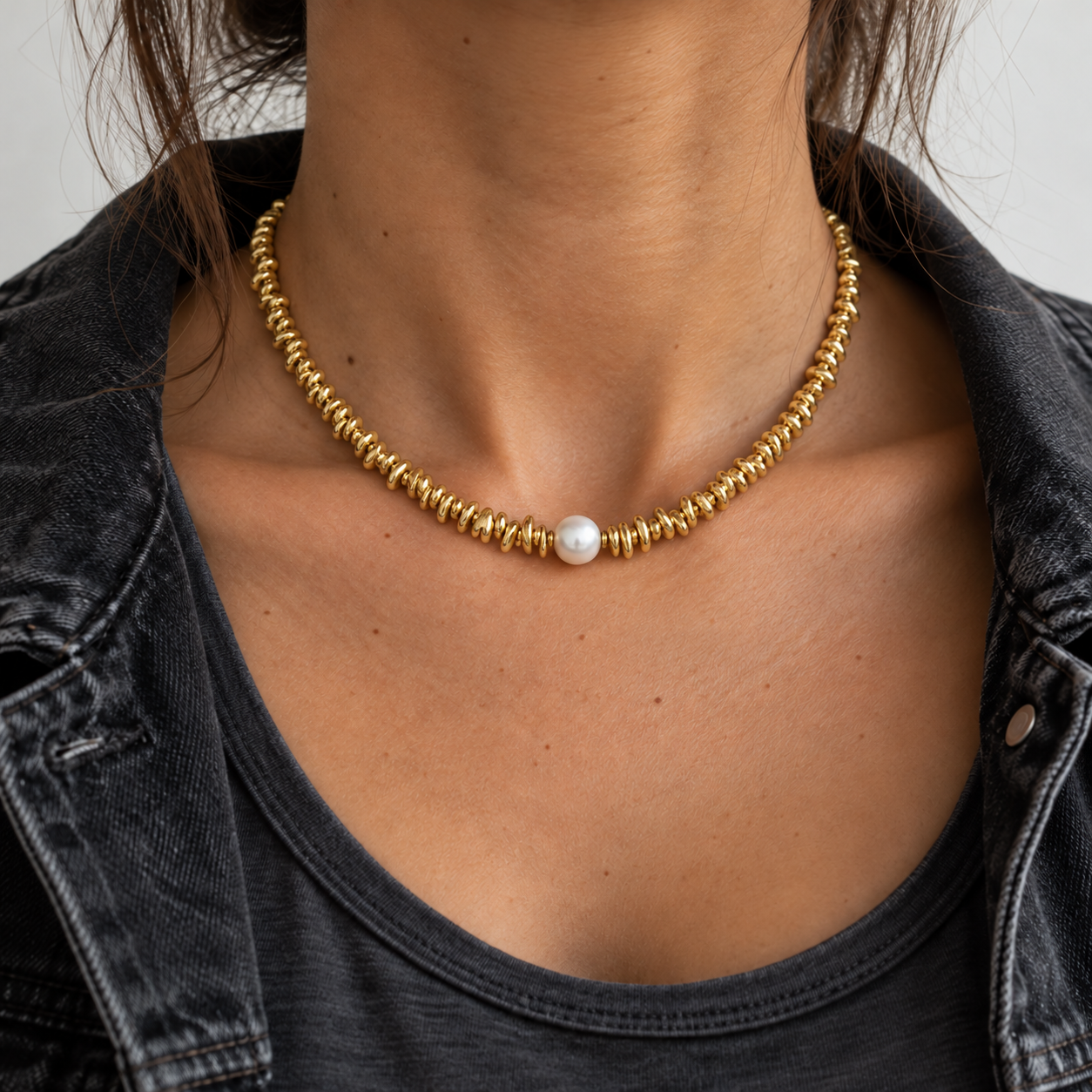 Collar Desfase Perla con piezas doradas irregulares, colocado en cuello natural con chaqueta vaquera
