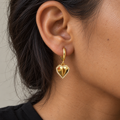Pendiente Heartbeat dorado con corazón facetado extraíble en una oreja, con luz natural