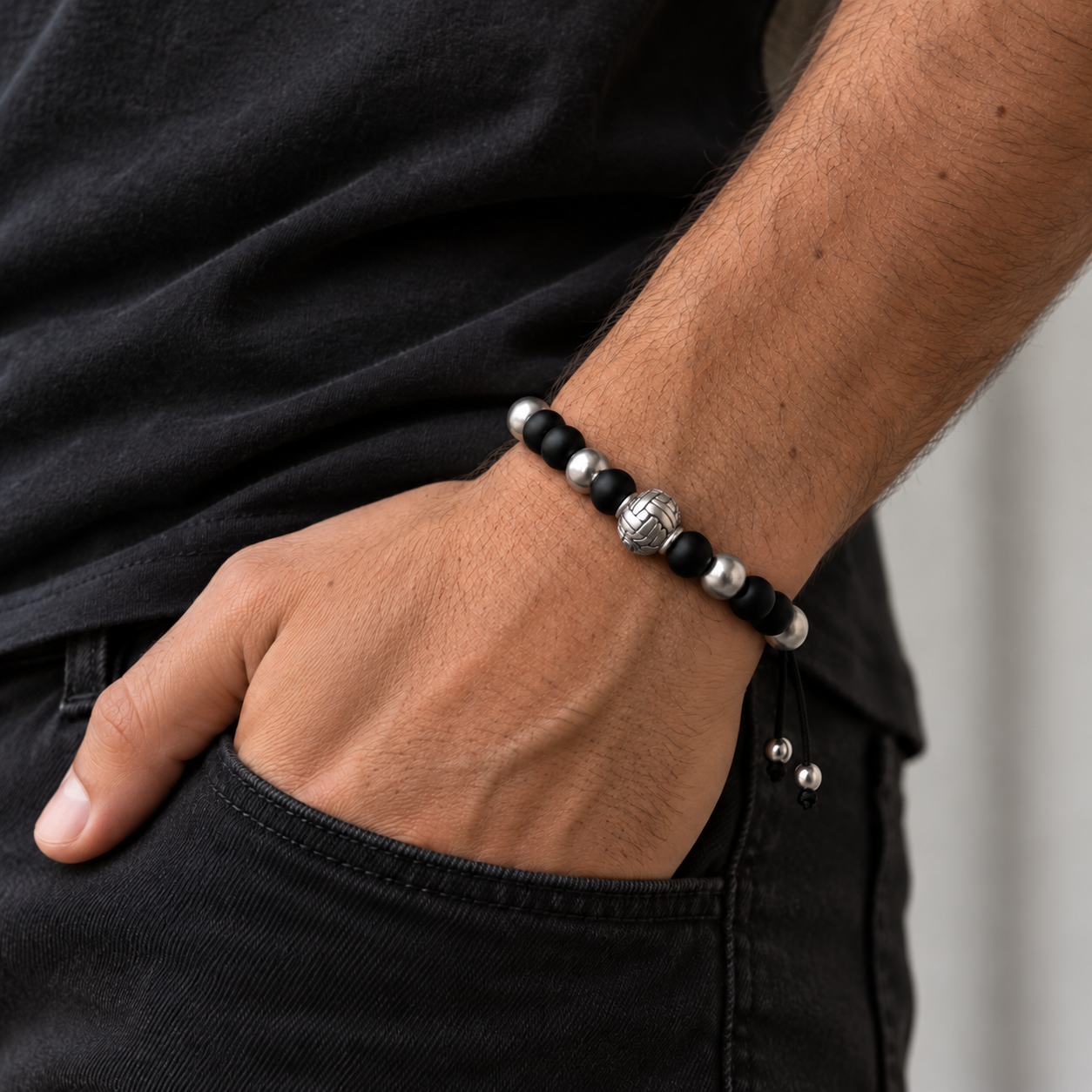 Pulsera Black Knot de piedra natural negra en muñeca masculina con cierre de cordón