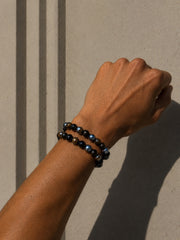 Dos pulseras Dark Matter de piedra natural combinadas sobre una muñeca